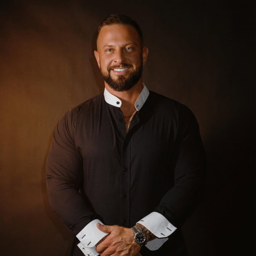 Caleb Scott, founder of the Man Days Movement — studio portrait in a black shirt against a warm brown backdrop